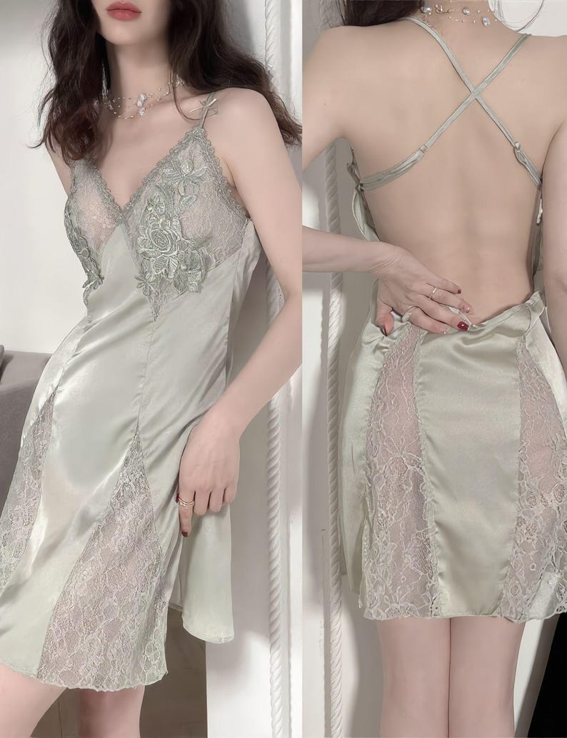 May include: Sage green satin slip dress with delicate lace detailing. The dress features a V-neckline with lace accents and a low back design. The lace is visible on the bodice and along the skirt's sides, creating a romantic and elegant look.