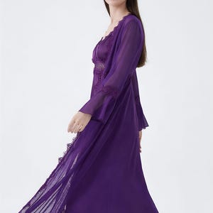 May include: A flowing, deep purple lingerie set. The set includes a long, sheer robe with lace trim and a matching slip. The fabric appears lightweight and the design is elegant. The robe has long sleeves and a V-neckline.