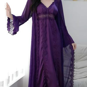 May include: A purple satin nightgown with lace detailing and a matching sheer robe. The robe has long sleeves with ruffled cuffs and a delicate lace trim. The nightgown features a V-neck and floral lace accents, creating an elegant and feminine look.