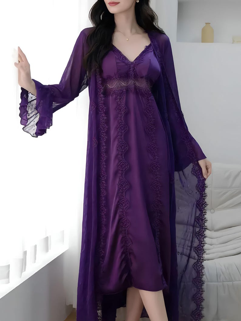 May include: A purple satin nightgown with lace detailing and a matching sheer robe. The robe has long sleeves with ruffled cuffs and a delicate lace trim. The nightgown features a V-neck and floral lace accents, creating an elegant and feminine look.