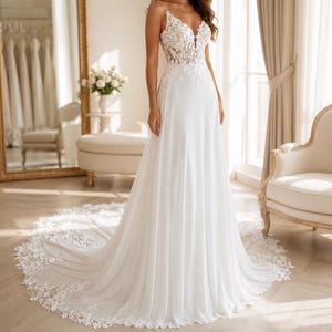May include: A floor-length white wedding dress featuring a sleeveless bodice with intricate floral lace appliques, a deep V-neckline, and a flowing skirt that transitions into a long, lace-trimmed train that spreads across the floor.