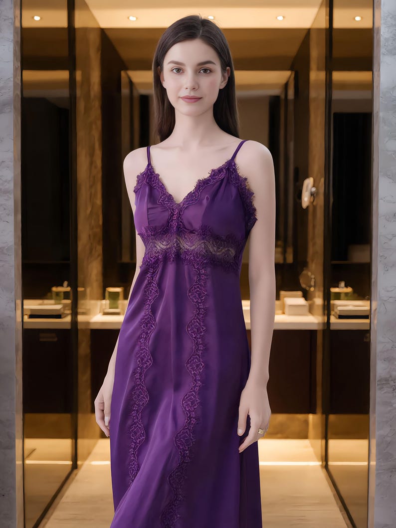 May include: A long, purple satin nightgown with delicate lace trim along the neckline and bodice. The dress features thin spaghetti straps and decorative lace detailing down the front. The nightgown is a deep shade of purple.