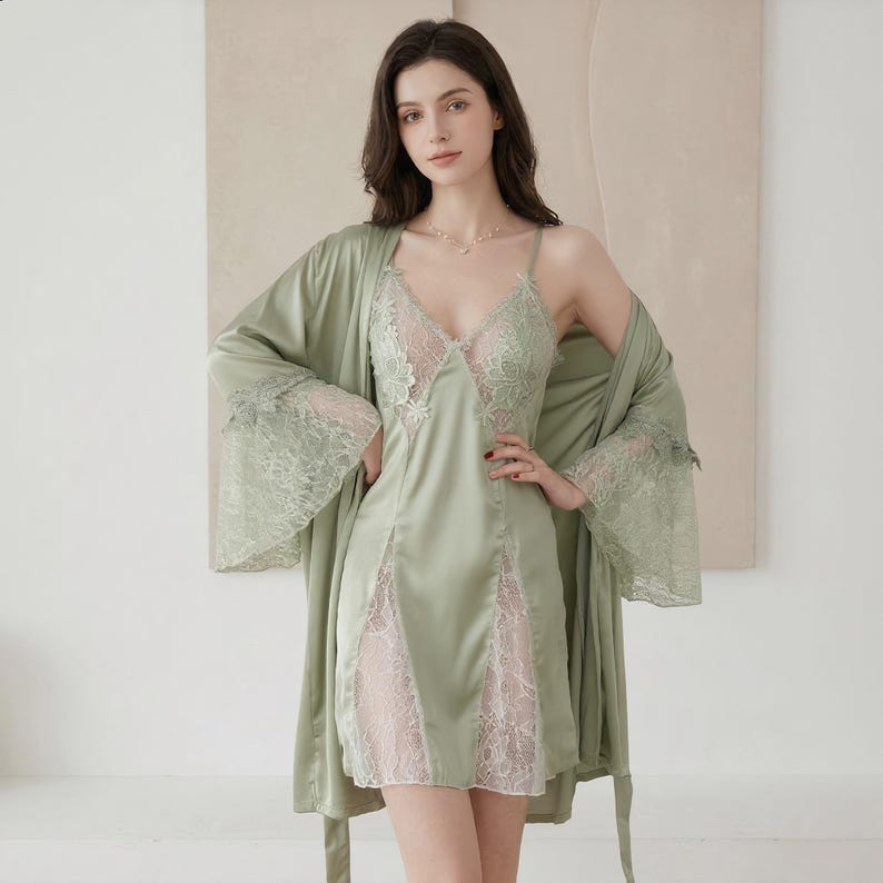May include: Sage green satin lingerie set featuring a slip dress with lace detailing and a matching robe. The slip dress has a V-neckline and lace inserts. The robe has wide sleeves with lace trim. A delicate and elegant sleepwear ensemble.