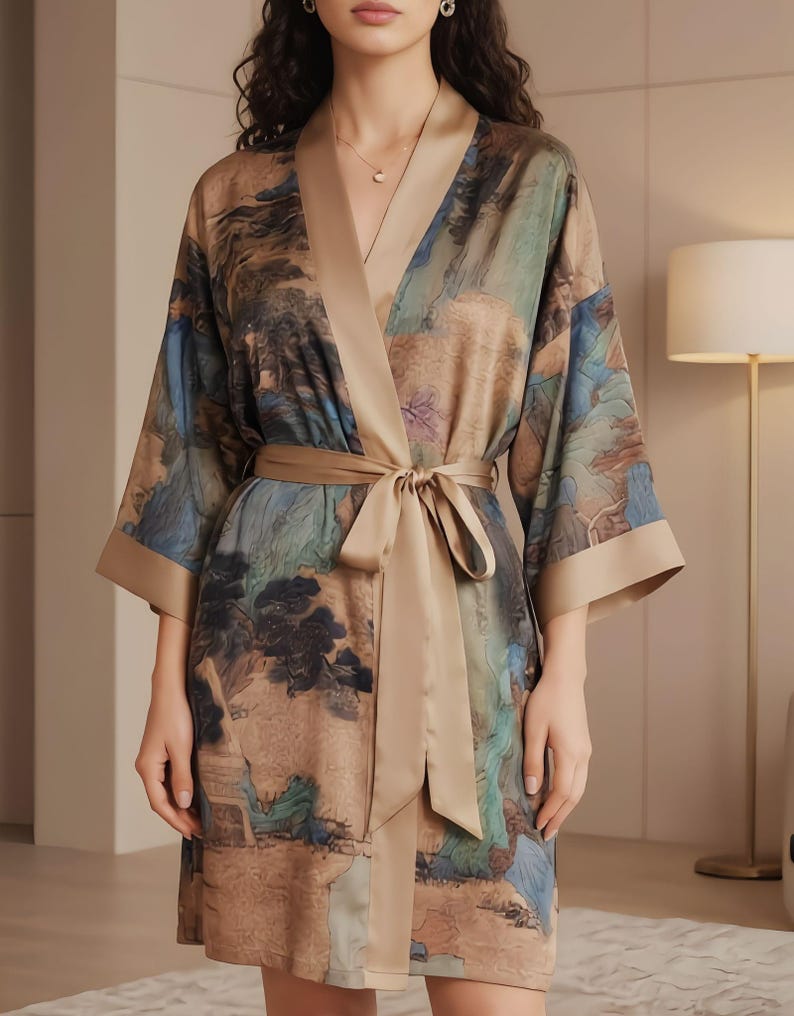 K&ouml;nnte beinhalten: Seidenrobe mit Landschaftsdruck in Braun-, Blau- und Gr&uuml;nt&ouml;nen. Die Robe hat eine beige Einfassung und einen passenden Bindeg&uuml;rtel. Die Robe hat weite &Auml;rmel und einen V-Ausschnitt.