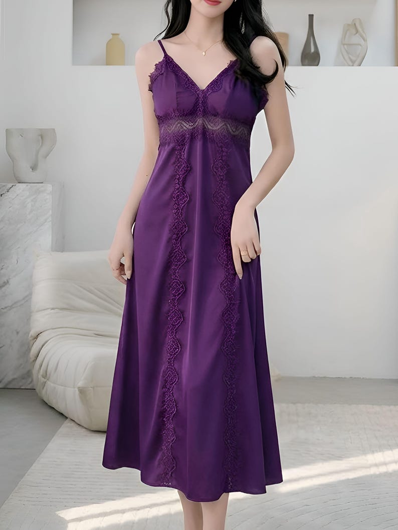 May include: A long, purple slip dress with delicate spaghetti straps and a V-neckline. The dress features intricate lace detailing along the bodice and down the front, creating a romantic and elegant look. The dress is made of a smooth, flowing fabric.