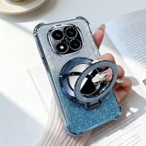 以下が含まれることがあります： キラキラ光る青とシルバーの携帯電話ケース、リングホルダー付き。ケースは透明なバンパーとキラキラのデザインです。リングホルダーは濃い青色で、シルバーのグリッターリングが付いています。