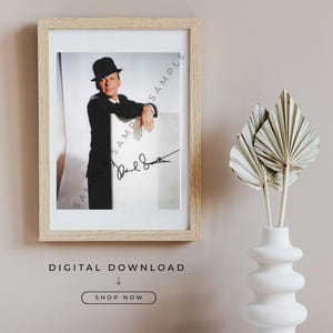 Peut inclure: Impression encadrée d'un homme en costume et chapeau noirs, appuyé sur une surface blanche. L'impression est dans un cadre en bois clair. L'image porte une signature et le mot "SAMPLE". Les mots "TÉLÉCHARGEMENT NUMÉRIQUE" et "ACHETER MAINTENANT" sont en dessous.