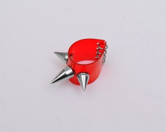 May include: Red plastic bracelet with silver spikes. The bracelet has a spring closure.