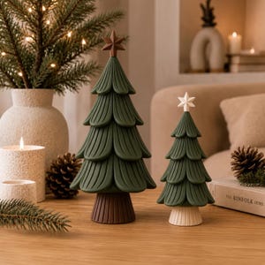 May include: Two decorative tabletop Christmas trees with dark green, layered, scalloped branches and a ribbed trunk. The taller tree features a brown star topper, while the shorter tree has a white star topper. Both are crafted with a smooth finish.