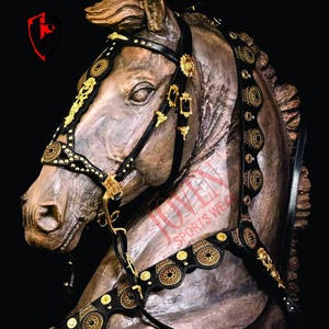 May include: A detailed sculpture of a horse head adorned with a black and gold bridle. The bridle features intricate gold embellishments and circular designs. The horse sculpture is a muted brown color, and the background is black.