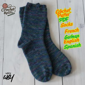 Peut inclure: Une paire de chaussettes tricotées à la main dans des tons de bleu, vert et violet. Les chaussettes sont faites avec un fil texturé et présentent un bord côtelé. L'image comprend le texte "Crochet By Gfx", "Crochet Pattern PDF Socks", et "very EASY".