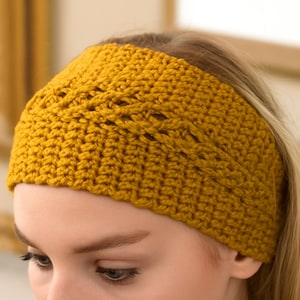 May include: Mustard yellow crocheted headband. The wide headband features a textured stitch pattern with a decorative openwork design across the top. The handmade accessory is shown on a person's head.