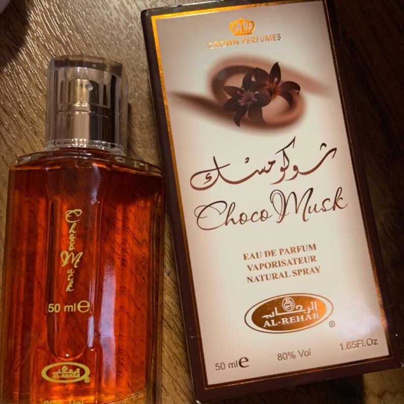 Puede incluir: Un frasco de perfume de vidrio marr&oacute;n con tapa plateada y las palabras "Choco Musk" impresas en el frasco. La caja de al lado tiene las palabras "Choco Musk" y "Crown Perfumes". El frasco contiene 50 ml.