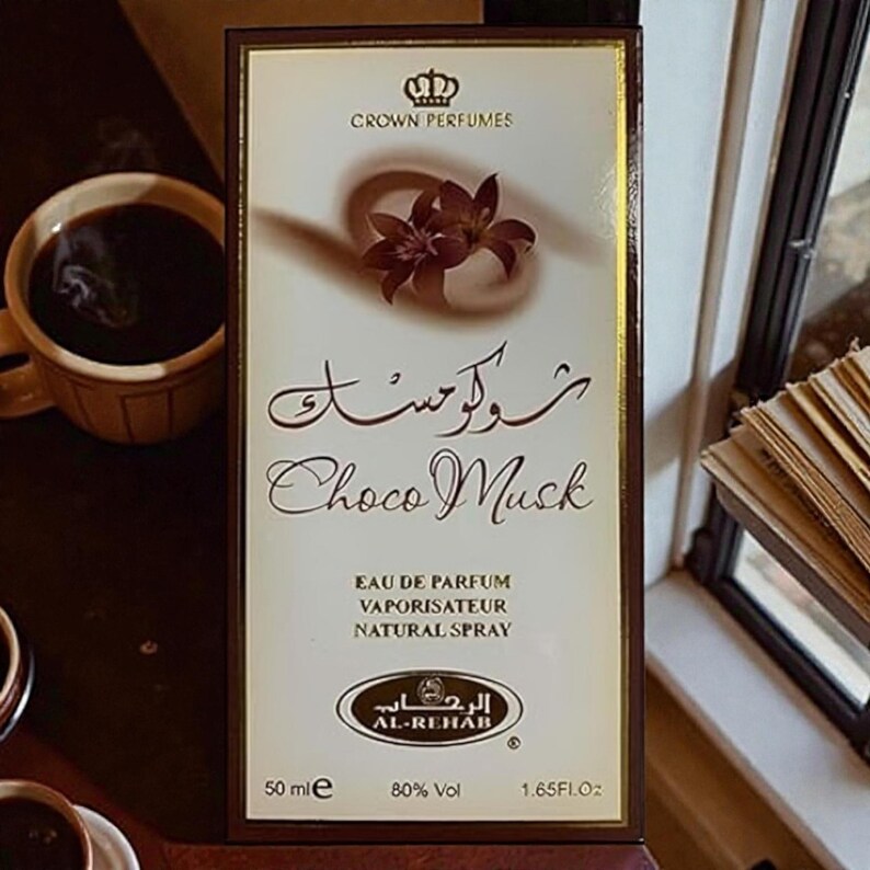 Puede incluir: Caja de perfume rectangular con borde dorado y fondo crema. La caja presenta el texto "Choco Musk" en ingl&eacute;s y &aacute;rabe, y la marca "Crown Perfumes". La caja indica que el perfume es de 50 ml y 1,65 fl oz.