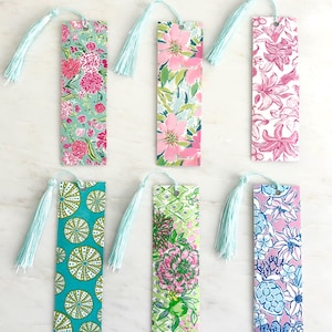 May include: Six rectangular bookmarks with floral and geometric patterns. Each bookmark has a light blue tassel attached at the top. The patterns include pink flowers, green leaves, and teal and white geometric designs.