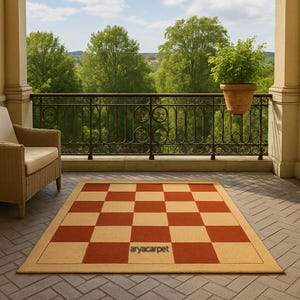 May include: A rectangular outdoor rug with a checkerboard pattern in red and beige. The rug has a beige border and the text "aryacarpet" in the lower right corner. The rug is on a patio.