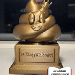 May include: A gold-colored trophy featuring a smiling poop emoji wearing a crown. The base of the trophy reads "Pingvinen" in embossed letters. The image also includes a license notice.