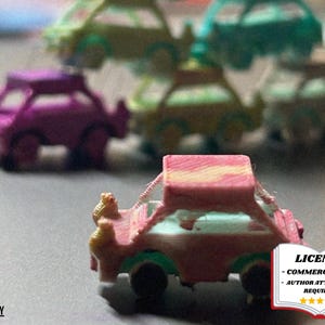 May include: A collection of miniature toy cars in various colors, including pink, purple, green, and yellow. The cars have a unique, textured design and are arranged in a group, with one car in sharp focus. The image includes a license graphic.