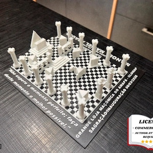 May include: A white 3D-printed model of a building complex with pillars and geometric shapes on a black and white checkered base. The model includes text in Portuguese and English. A license badge is in the bottom right corner.