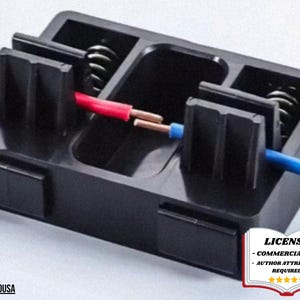 May include: A black electrical wire connector with red and blue wires inserted. The connector has a rectangular shape with internal compartments and metal springs. The image also includes a license badge in the bottom right corner.