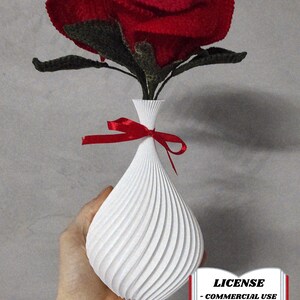 May include: A handmade red rose with green leaves sits in a white vase with a spiral design. A red ribbon is tied around the vase. The image includes the text "LICENSE - COMMERCIAL USE - AUTHOR ATTRIBUTION REQUIRED".