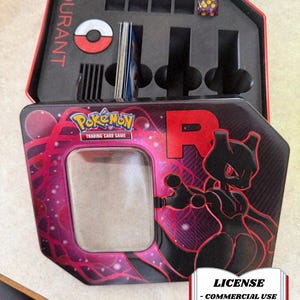 May include: Open black and red Pokemon Trading Card Game storage tin. The lid features the word "DURANT" in red. The front of the tin has a graphic of Mewtwo and the text "Pokemon Trading Card Game". Includes a dice and card slots.