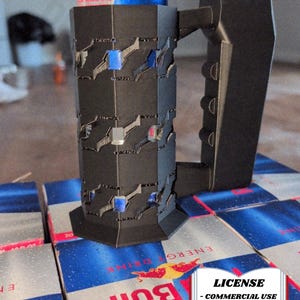 Könnte beinhalten: Ein schwarzer, geometrischer Dosenhalter mit Griff, der eine Red Bull Energydrink-Dose hält. Der Halter hat ein gemustertes Design mit blauen und grauen Akzenten. Der Text "LICENSE - COMMERCIAL USE - AUTHOR ATTRIBUTION REQUIRED" ist sichtbar.