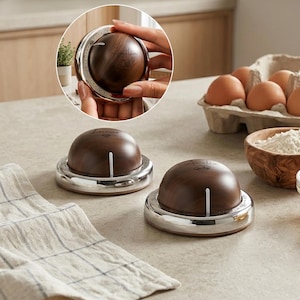 May include: Two round kitchen timers with a dark wood grain finish and a silver metallic base. Each timer features a white vertical indicator line and custom text engraved on the top surface, with one reading Lucas and the other reading Amelia.