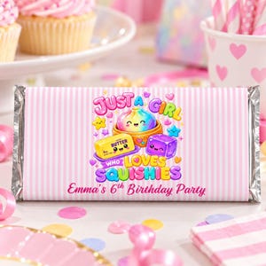 Pode incluir: Uma embalagem retangular de barra de chocolate com um padrão de listras verticais rosa claro e branco. O centro apresenta um gráfico colorido de um bolinho arco-íris, um tablete de manteiga e um cubo roxo com rostos, com o texto Just A Girl Who Loves Squishies e Emma's 6th Birthday Party.