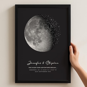 Könnte beinhalten: Schwarz gerahmter Druck mit einem detaillierten Graustufenbild des Mondes und einem Sterneneffekt. Der Druck enthält die Namen "Jennifer & Stephen" und den Text "THE NIGHT OUR ADVENTURE BEGAN..." mit Ort und Datum.