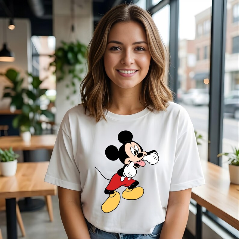 Puede incluir: Camiseta blanca con una imagen de dibujos animados de Mickey Mouse. El personaje est&aacute; representado con su atuendo cl&aacute;sico: pantalones cortos rojos, zapatos amarillos y guantes blancos. Una prenda casual para el d&iacute;a a d&iacute;a.