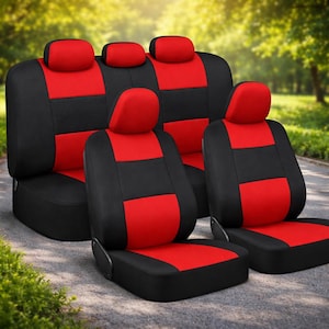 Puede incluir: Un juego de fundas de asiento de coche negras y rojas. Las fundas están divididas en secciones negras y rojas. Los reposacabezas son rojos. Los asientos están colocados sobre una superficie gris con un fondo verde borroso.