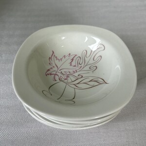 May include: A stack of white ceramic bowls with a rounded square shape. Each bowl features a central line-art illustration of a maple leaf and an oak leaf in a dark reddish-brown color, centered on the interior base of the white ceramic surface.