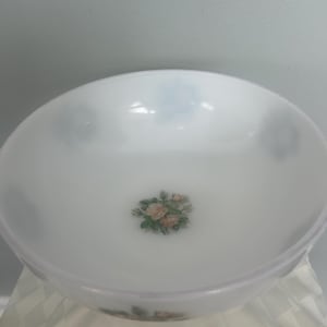 May include: A white, round serving bowl with a floral rose design in the center. The bowl has a slightly flared rim and a smooth, opaque finish. The roses are in shades of pink, peach, and green.