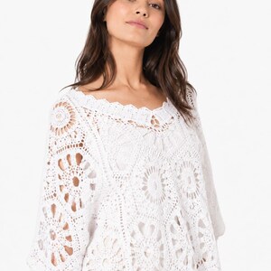 May include: White crochet top with a scalloped neckline and short sleeves. The openwork design features circular and floral patterns. The top is made of a soft, lightweight material, perfect for warm weather.