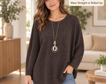 May include: A dark brown long-sleeve jumper with a round neckline and a loose fit. A long necklace with colourful beads and a gold circular pendant is worn over the jumper. Text on the image reads: Full-Length Sleeves - Wear Straight or Rolled Up.