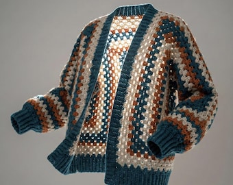 May include: A handmade, open-front crochet cardigan in a granny square pattern. The sweater features a color block design with teal, cream, and rust-colored yarn. The sleeves and trim are a solid teal color, and the overall style is a relaxed fit.