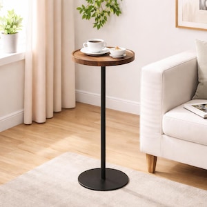 May include: A small, round side table with a dark wood top and a black metal base. A white teacup and saucer, along with a small bowl, sit on the table. The table is approximately 28 inches tall.