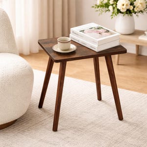 May include: A small, square, dark brown side table with four angled legs. A cup and saucer sit on top, along with two books. The table is made of wood and has a warm, inviting appearance. The table is approximately 20 inches tall.