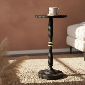 May include: A black side table with a round top and base, featuring a decorative, turned column. The table has gold-colored accents and a small white mug with a coaster on top. The table is approximately 24 inches tall.