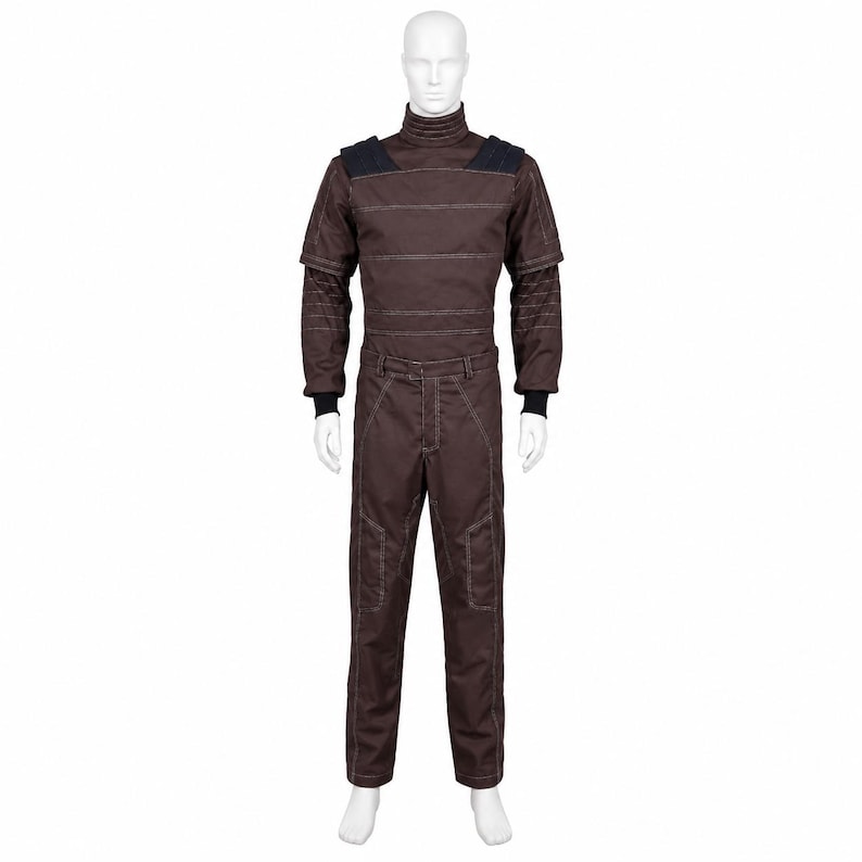 May include: A dark brown jumpsuit featuring a high mock neck collar, horizontal white stitching across the chest, and dark navy shoulder panels. The long sleeves have black ribbed cuffs, and the trousers include reinforced knee sections.