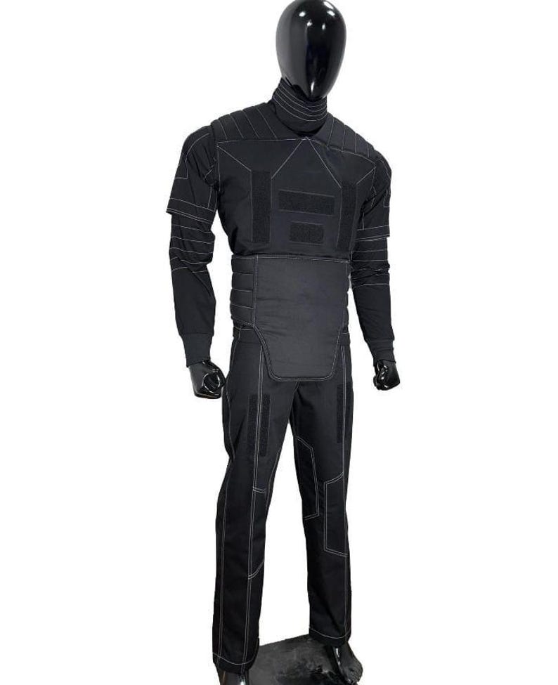 Pu&ograve; includere: Tuta tattica nera con cuciture bianche, esposta su un manichino. La tuta comprende un top a maniche lunghe, pantaloni e un giubbotto protettivo. Il manichino ha testa e mani nere.