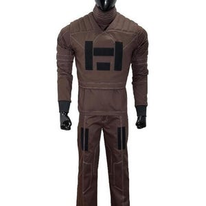 Puede incluir: Mono marr&oacute;n con cuello alto y mangas largas, exhibido en un maniqu&iacute;. El traje presenta un gran dise&ntilde;o rectangular negro en el pecho y parches negros en los pantalones. Las costuras blancas delinean las costuras.