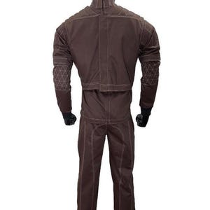 Puede incluir: Traje protector marr&oacute;n con costuras blancas, exhibido en un maniqu&iacute;. La chaqueta tiene paneles acolchados en los hombros y la parte superior de la espalda, con coderas con dise&ntilde;os geom&eacute;tricos. El pantal&oacute;n es de corte recto. El traje est&aacute; dise&ntilde;ado para protecci&oacute;n.