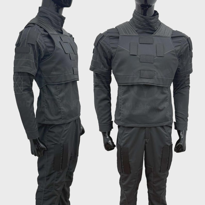 May include: A black tactical uniform set consisting of a long-sleeved shirt with a high collar, a chest plate with rectangular patches, and matching trousers. The garment features reinforced stitching, shoulder panels, and rectangular leg pockets.