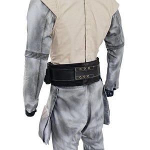 May include: A light gray jumpsuit with a cream-colored vest and a black belt. The jumpsuit has a textured appearance and features pockets on the legs. The vest has a quilted design on the shoulders.