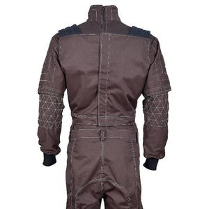 May include: A dark brown jumpsuit featuring a high collar, long sleeves with quilted triangular patterns on the forearms, and black ribbed cuffs. The garment includes prominent white topstitching throughout, shoulder padding, and a central vertical seam.