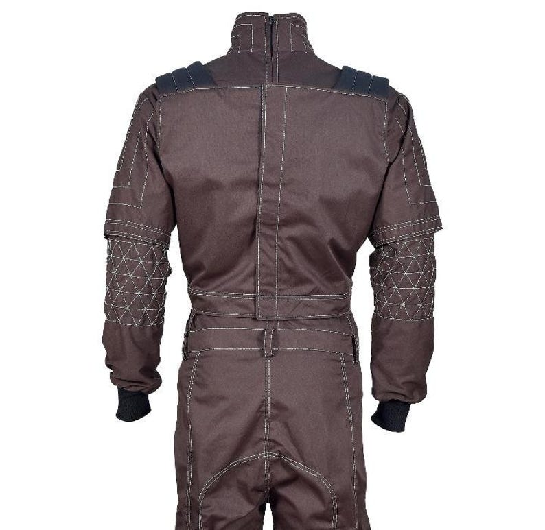 May include: A dark brown jumpsuit featuring a high collar, long sleeves with quilted triangular patterns on the forearms, and black ribbed cuffs. The garment includes prominent white topstitching throughout, shoulder padding, and a central vertical seam.