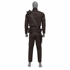 May include: A brown costume displayed on a mannequin. The outfit includes a jacket with shoulder accents, a belt with pouches, and matching pants. A strap crosses the chest. The costume is designed with visible stitching.