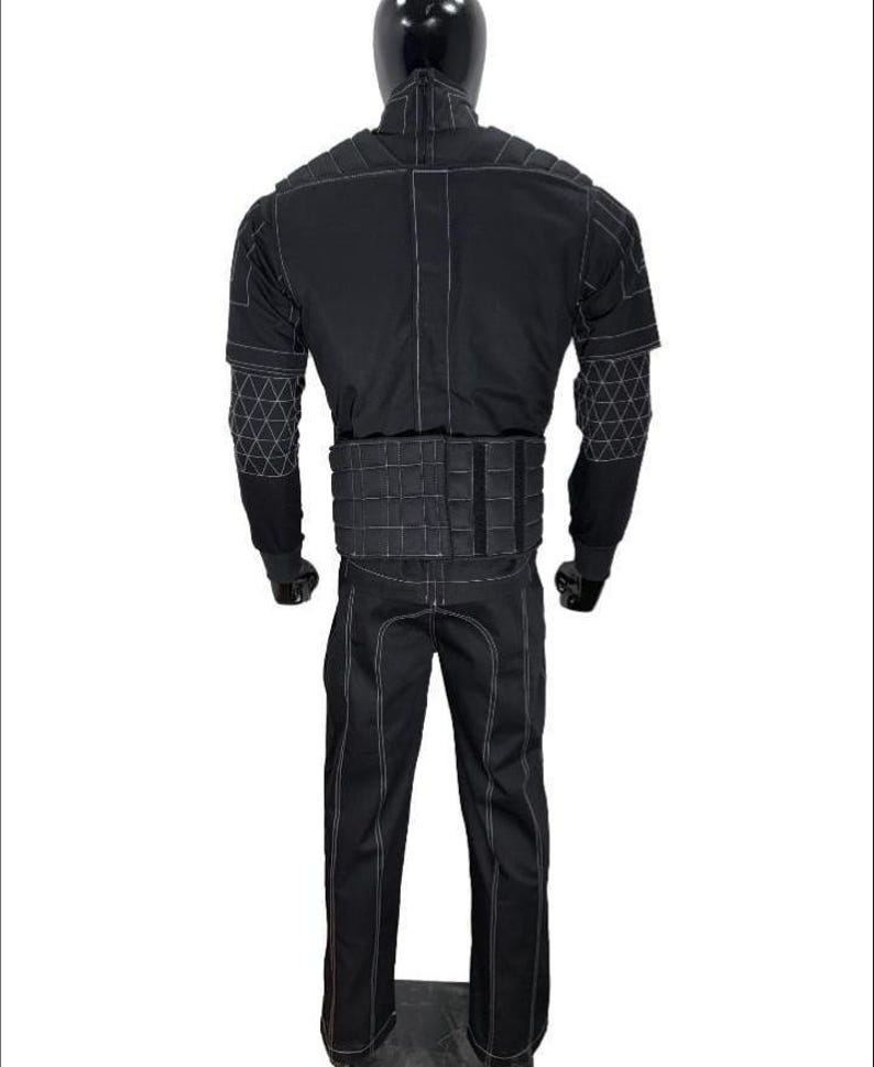 May include: A black tactical suit displayed on a mannequin. The suit features white stitching, a quilted vest, and geometric patterns on the sleeves. The pants have a straight leg design.